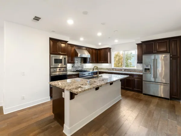 a kitchen with stainless steel appliances granite countertop a sink a stove a refrigerator and a microwave