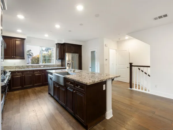 a kitchen with stainless steel appliances granite countertop a stove a sink dishwasher a refrigerator and a oven with wooden floor