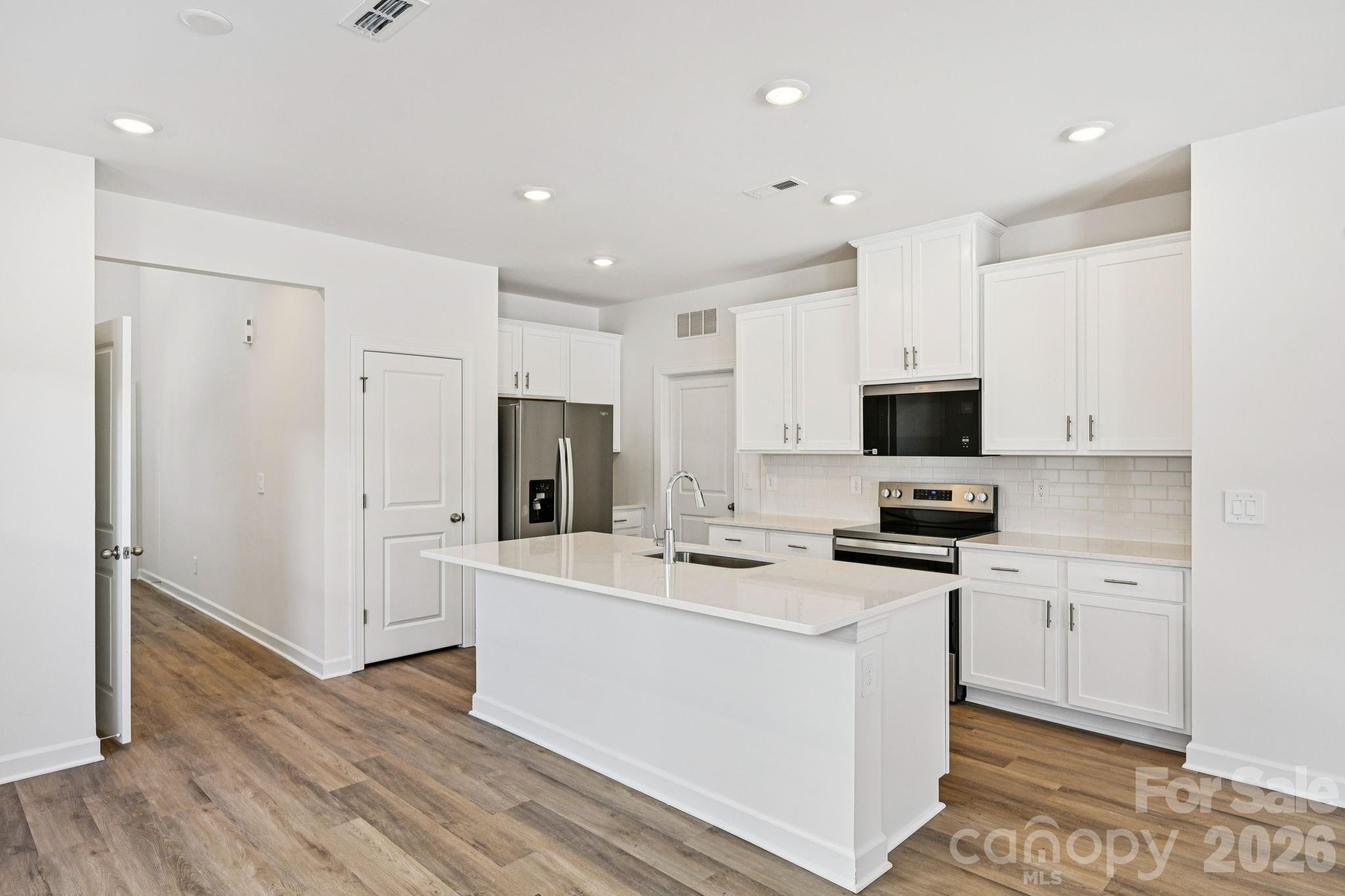1281 30th St Lane Northeast Conover, NC 28613 - Photo 8 of 37 a kitchen with stainless steel appliances a stove top oven a refrigerator a sink and white cabinets with wooden floor