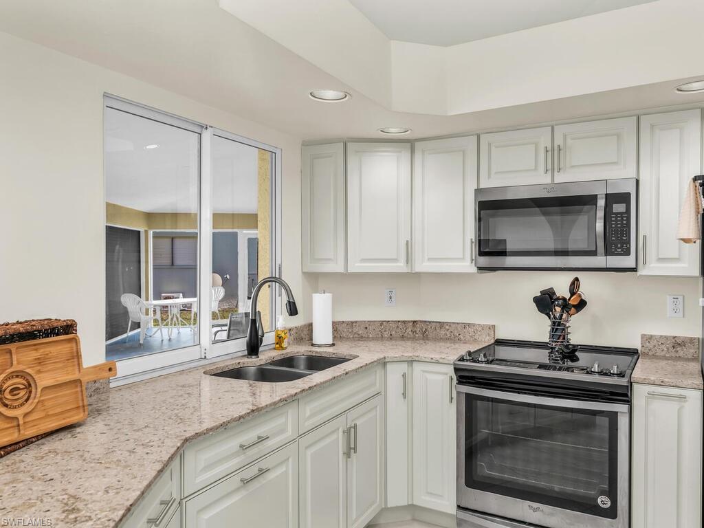 111 Morning Star Cay Naples, FL 34114 - Photo 13 of 47 a kitchen with stainless steel appliances granite countertop a stove a sink and a microwave