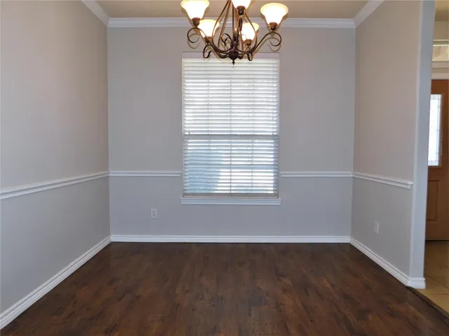a view of an empty room with wooden floor and a ceiling fan