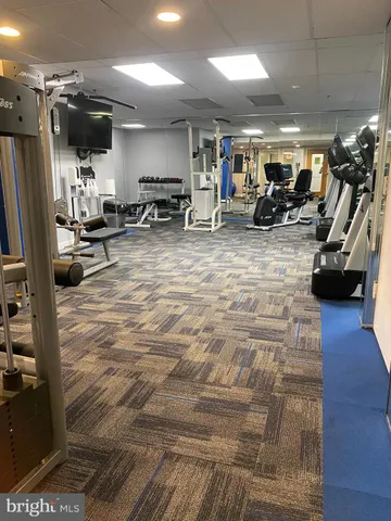 a living room with couches a flat tv screen and kitchen view