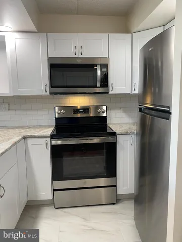 a kitchen with stainless steel appliances granite countertop a refrigerator a sink a stove a microwave and wooden floor