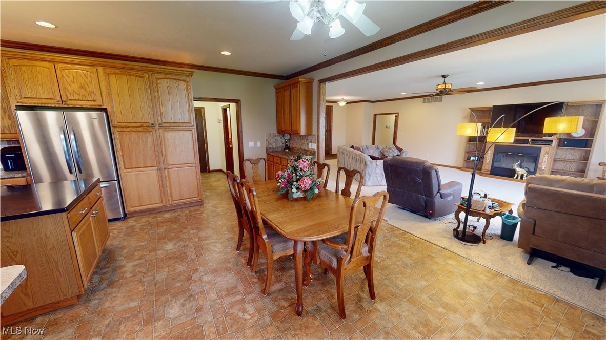 10323 Smith Road Litchfield, OH 44253 - Photo 10 of 50 Dining space with crown molding, recessed lighting, a glass covered fireplace, and a ceiling fan