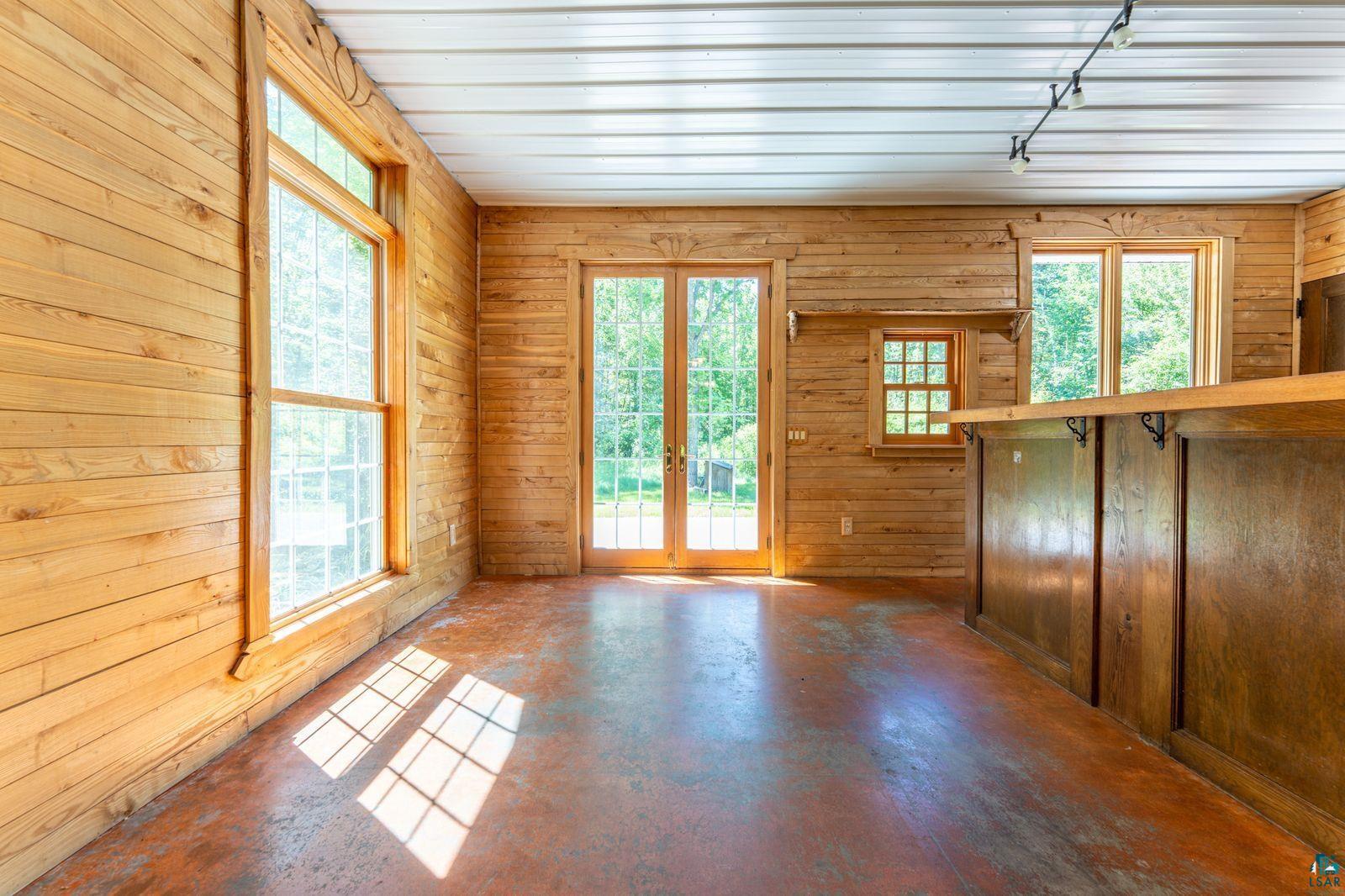 9734 Alango Road Angora, MN 55703 - Photo 7 of 41 Interior space featuring extensive wood paneling, a large double-hung window, and a built-in wood bar