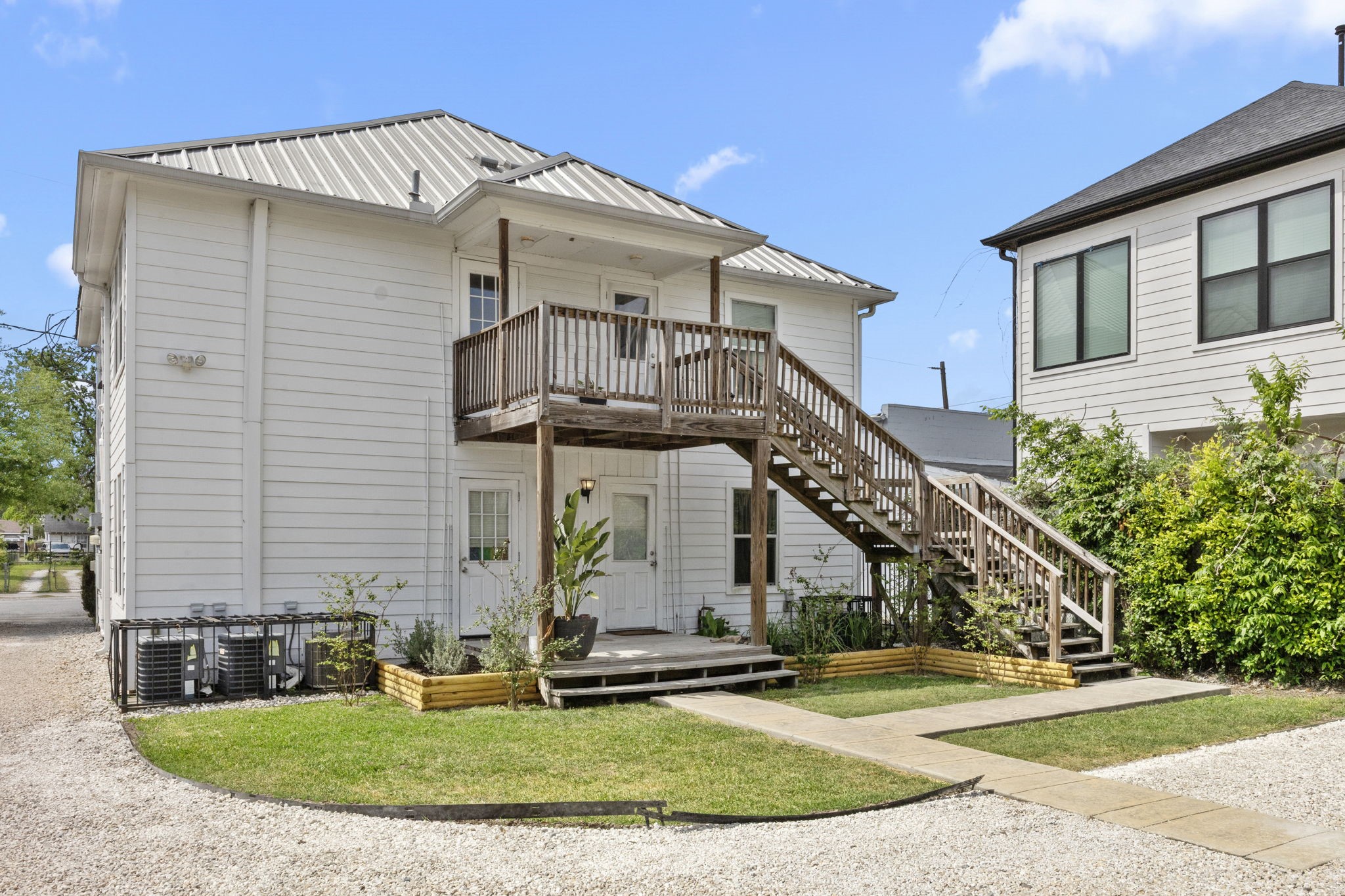 7 Latham Street Houston, TX 77011 - Photo 20 of 23 Well-maintained rear exterior featuring private entrances, an elevated balcony, and exterior staircase access, complemented by neatly landscaped grounds.