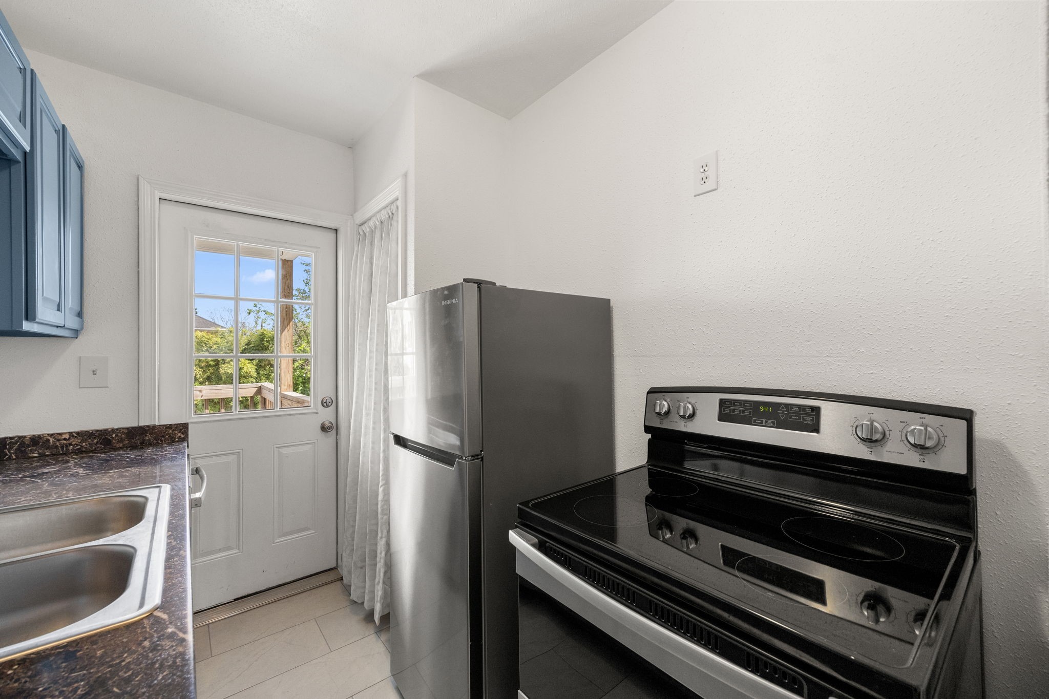 7 Latham Street Houston, TX 77011 - Photo 8 of 23 Equipped with modern appliances, including a sleek range and refrigerator, with convenient access to the back patio.