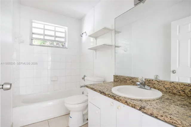 a bathroom with a granite countertop sink a toilet and shower