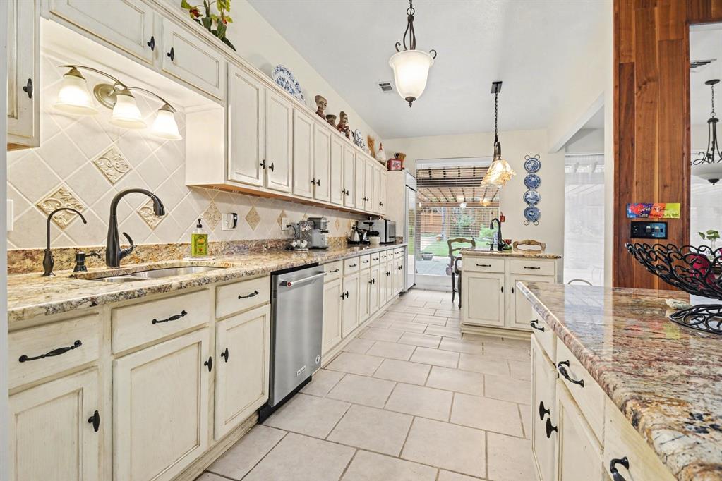 14140 Hillcrest Road Dallas, TX 75254 - Photo 10 of 29 a kitchen with kitchen island granite countertop a stove a sink and white cabinets with wooden floor