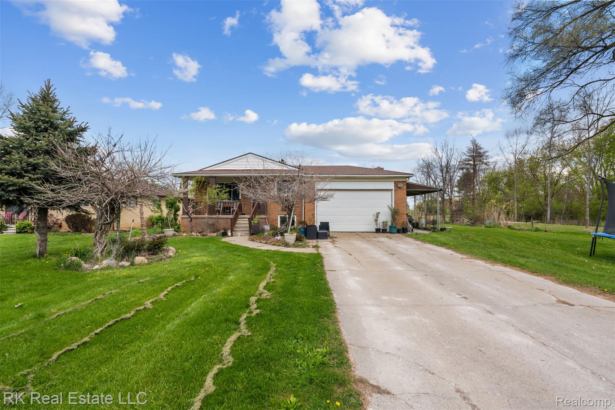 Ranch-style house featuring a front lawn, an attached garage, concrete driveway, and covered porch