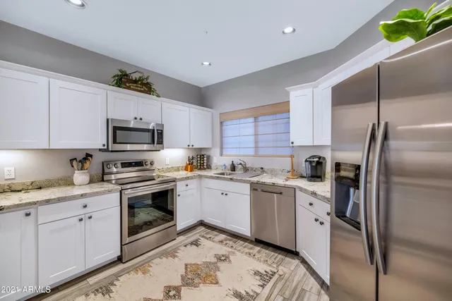 a kitchen with stainless steel appliances granite countertop a sink and a refrigerator