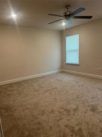 an empty room with a window and a fan
