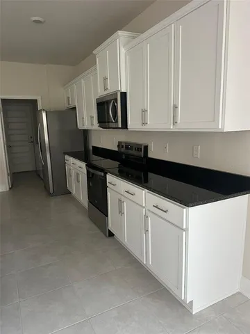 a kitchen with stainless steel appliances granite countertop white cabinets and refrigerator