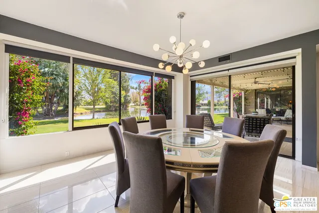 a view of a dining room with furniture large windows a chandelier and wooden floor