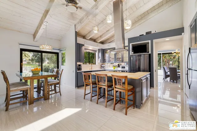 a dining hall with stainless steel appliances kitchen island granite countertop a dining table and chairs