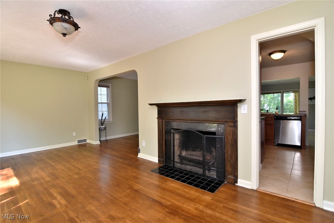 3679 Fenley Road Cleveland Heights, OH 44121 - Photo 4 of 45 Unfurnished living room featuring arched walkways, a tiled fireplace, and dark wood-type flooring