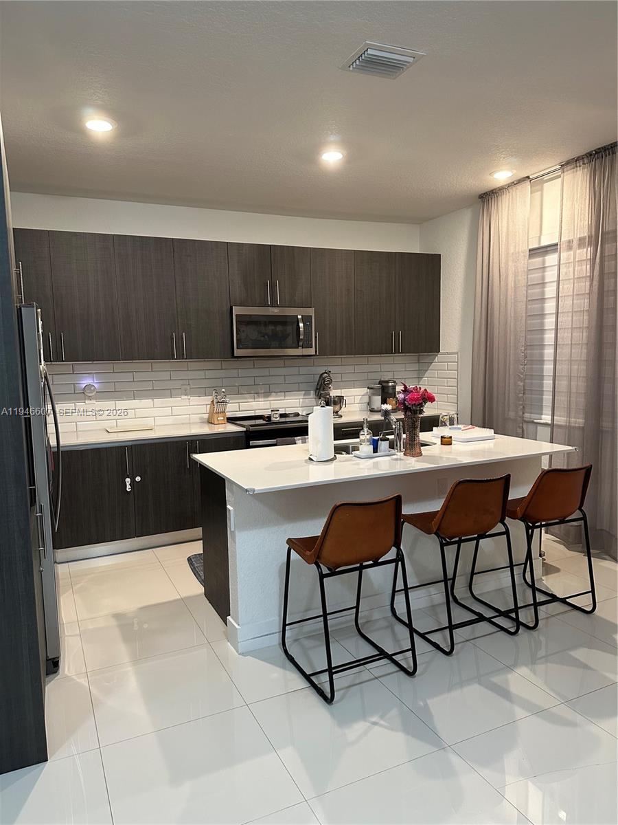 507 Southwest 91st Court, Unit 507 Miami, FL 33174 - Photo 2 of 15 a kitchen with stainless steel appliances kitchen island granite countertop a sink and cabinets