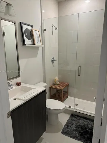 a bathroom with a sink a toilet a mirror and shower