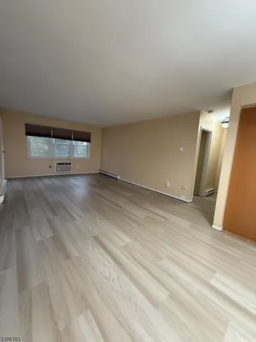 an empty room with wooden floor and window