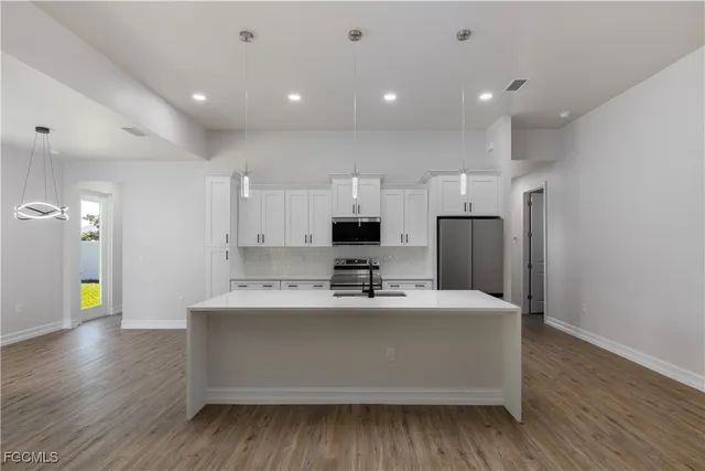a kitchen with kitchen island stainless steel appliances a sink and a refrigerator
