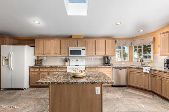 a kitchen with stainless steel appliances granite countertop a stove top oven a sink a refrigerator and white cabinets