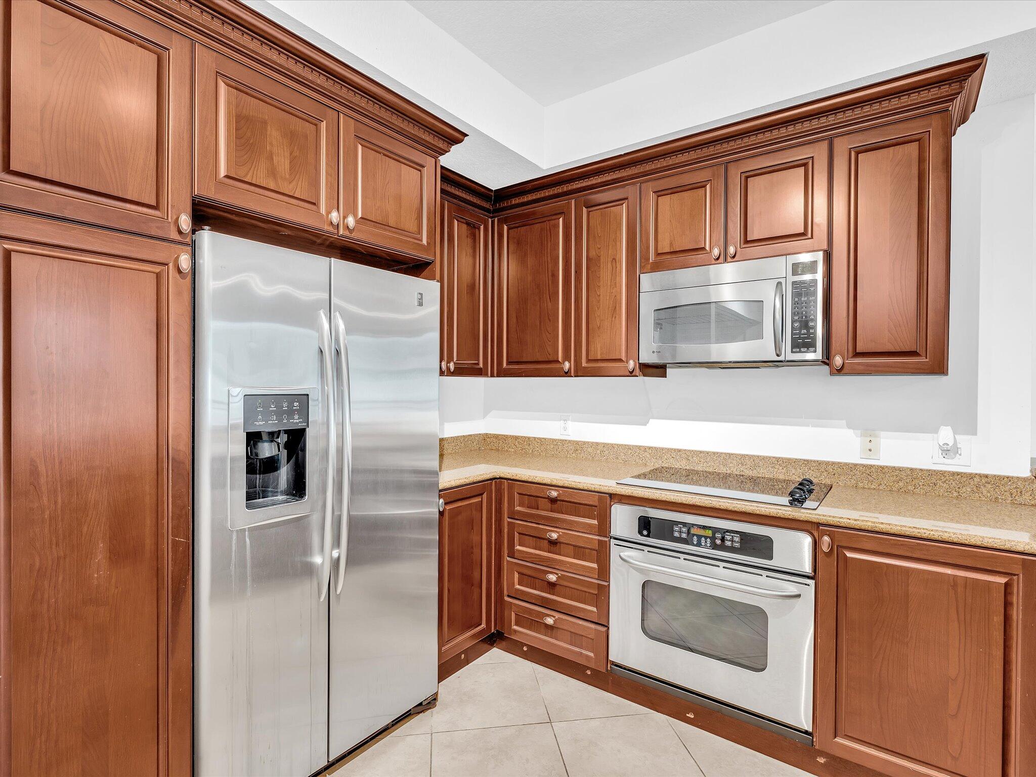 4303 Renaissance Way, Unit 303 Boynton Beach, FL 33426 - Photo 26 of 74 a kitchen with stainless steel appliances granite countertop a refrigerator and a stove top oven