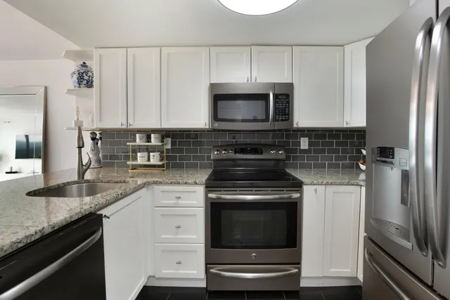 a kitchen with granite countertop a sink stove and refrigerator