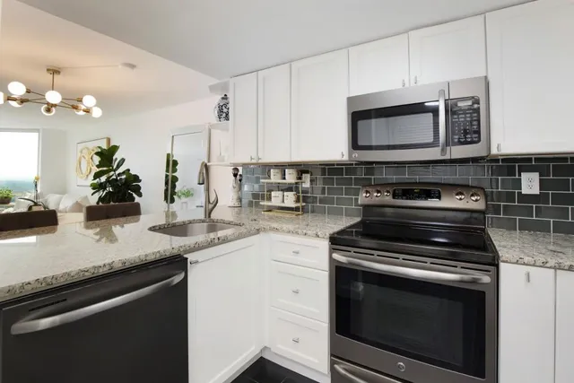 a kitchen with granite countertop a stove a microwave a sink and cabinets