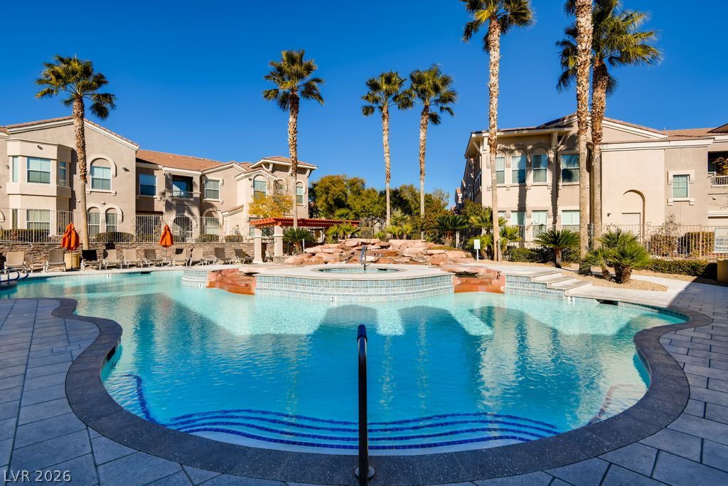 10550 West Alexander Road, Unit 1108 Las Vegas, NV 89129 - Photo 21 of 29 Community pool & spa, with lush palm trees framing the area.