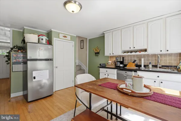 a kitchen with stainless steel appliances granite countertop a refrigerator a stove a sink and white cabinets with wooden floor