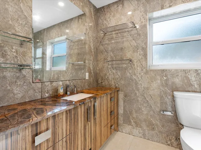 a bathroom with a granite countertop sink a toilet and shower