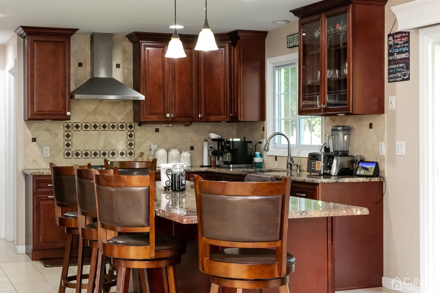 8 Peppermint Hill Road North Brunswick, NJ 08902 - Photo 18 of 32 a kitchen with stainless steel appliances granite countertop a stove top oven a sink a dining table and chairs with wooden floor
