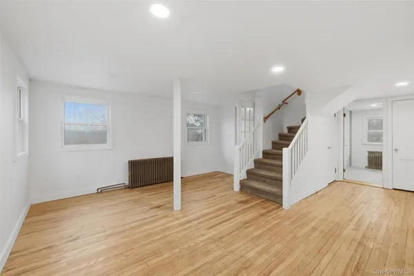a view of an empty room with wooden floor and stairs