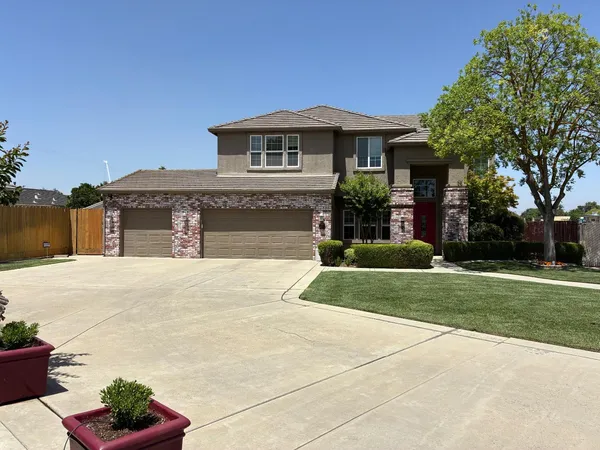 a front view of a house with garden and trees