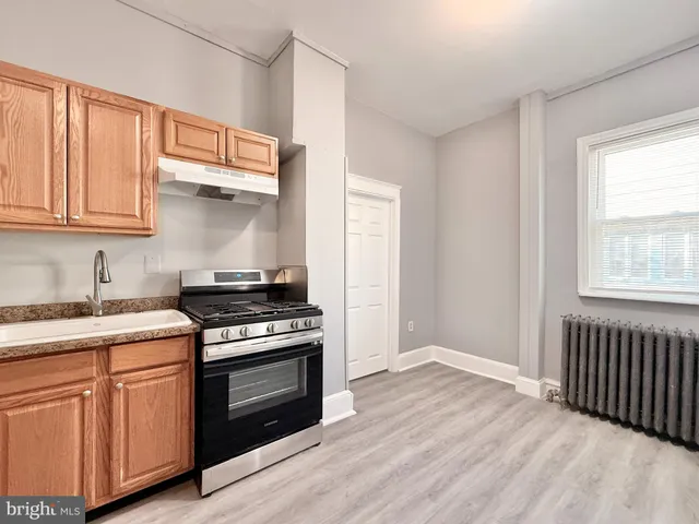 a kitchen with granite countertop wooden cabinets stove and sink