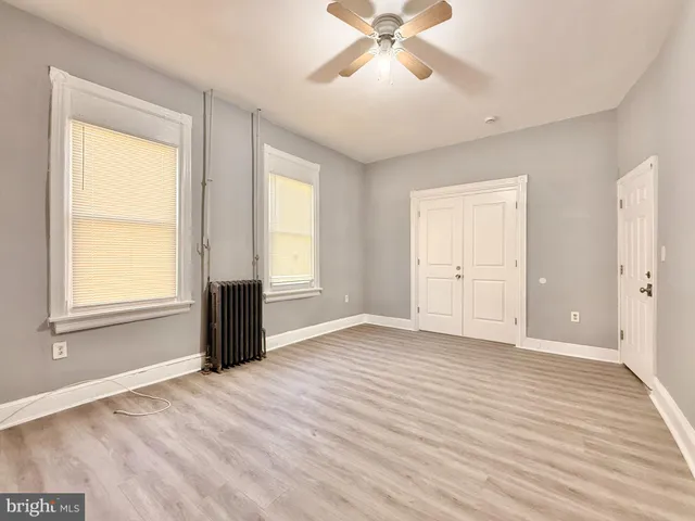 a view of an empty room with a window and wooden floor