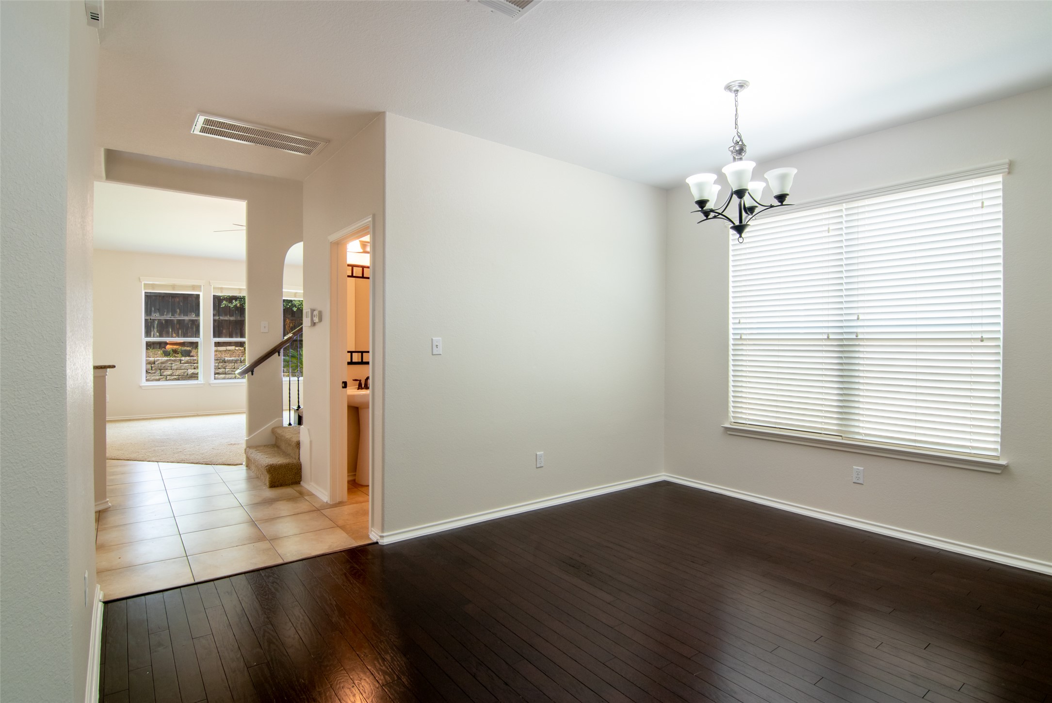 12104 Broten Street Austin, TX 78748 - Photo 13 of 32 Rich hardwood floors complement a modern chandelier in this inviting dining space.
