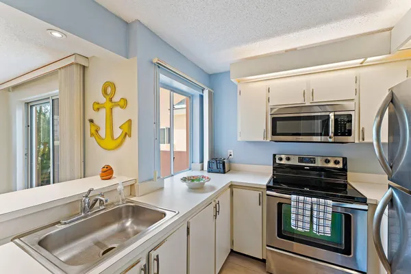 a kitchen that has a sink and a stove with wooden floor
