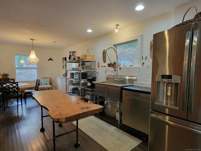 a kitchen with stainless steel appliances granite countertop sink refrigerator dining table and chairs
