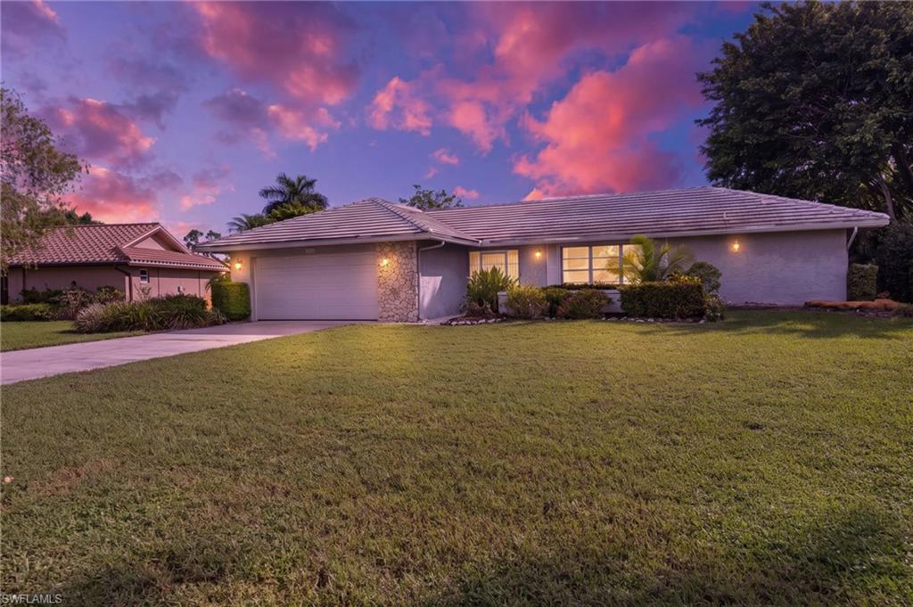 379 Torrey Pines Point Naples, FL 34113 - Photo 21 of 21 Stone accent facade with a tiled roof, mature landscaping, and an attached two-car garage