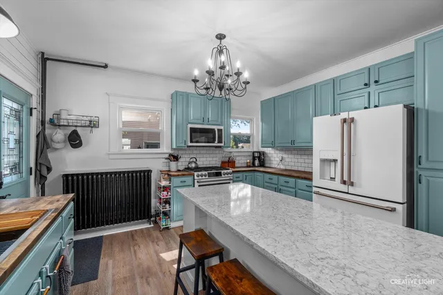 a kitchen with a refrigerator a sink dishwasher a oven with a dining table and chairs