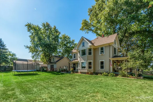 a view of a yard in front of a house with plants and large tree
