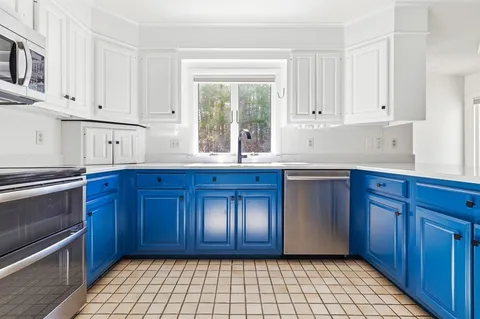 a kitchen with granite countertop wooden cabinets stainless steel appliances and a window