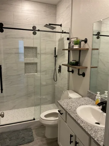 a bathroom with a granite countertop sink a toilet and shower