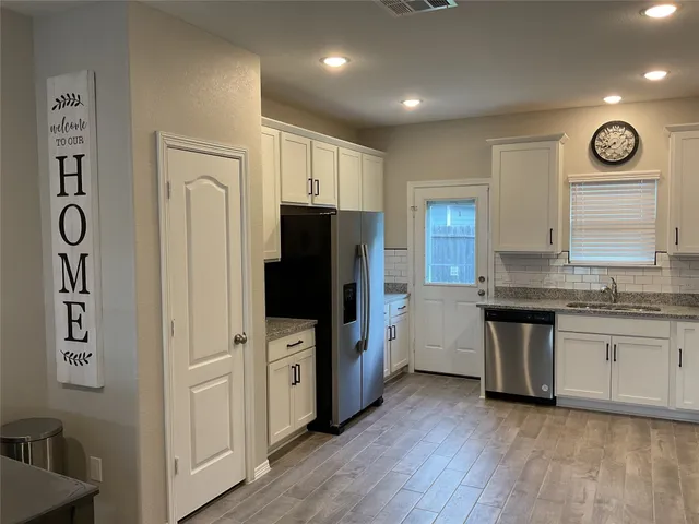 a kitchen with stainless steel appliances granite countertop a refrigerator a stove and a sink