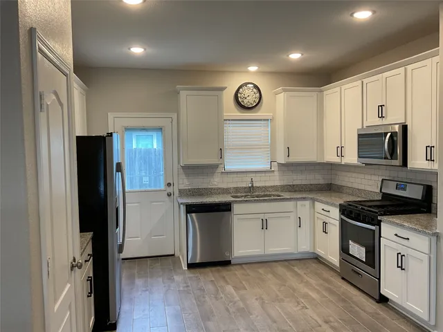 a kitchen with granite countertop a stove top oven microwave and refrigerator