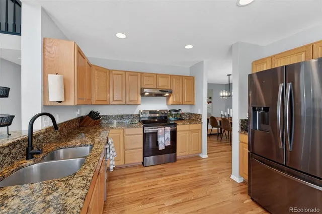 a view of a dining room and livingroom with furniture wooden floor a chandelier