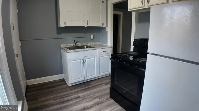 a kitchen with granite countertop white cabinets and black appliances