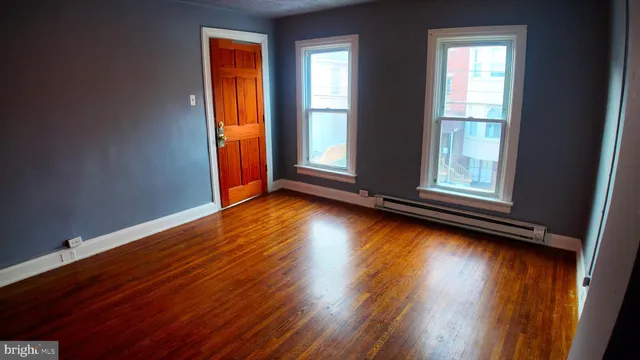 an empty room with wooden floor and windows