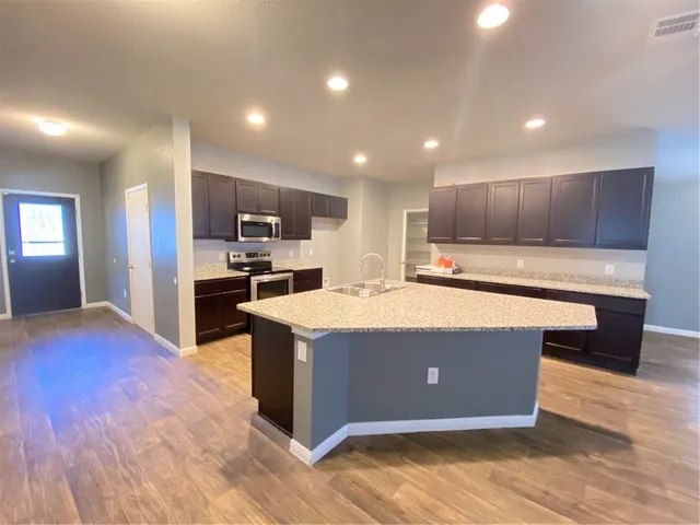 a kitchen with kitchen island granite countertop wooden floors and stainless steel appliances